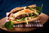A sandwich with minced meat, cheese and lambs lettuce