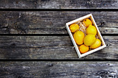 Lemons in a wooden crate on a wooden surface (seen from above)