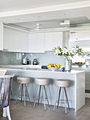 Barstools at island counter with glossy white cabinets