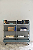 Books on simple metal shelves on castors against white wall