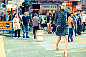 Junge Frau in blau gemustertem Mantel auf der Straße