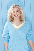 Junge blonde Frau in blauem Pulli mit gelbem Unterziehshirt