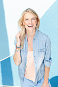 A young blonde woman wearing a denim shirt over a light top