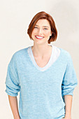 A red-haired woman wearing a blue jumper over a white top