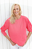 A blonde woman wearing a pink blouse