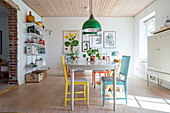 Colourful chairs around old dining table in dining room
