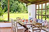 Gedeckter Tisch auf überdachter Terrasse im sommerlichen Garten