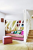 Rosafarbenes Sofa mit bunten Kissen neben der Treppe