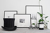 Houseplant, miniature Eiffel towers, framed black-and-white photos and opt hat on surface