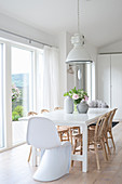 Designer chair and rattan chairs around table in white dining room