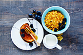 Breakfast theme with corn flakes, grilled toasts, milk, honey, grapes and fresh blackberries on vintage wooden background