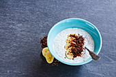 Breakfast almond milk chia seed pudding with banana and chocolate in bowl over grey stone background