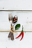 Spices, red hot chili peppers with vintage fork and spoon on white wooden background