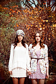 Two young women standing in front of an autumnal bush