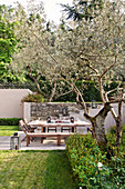 Gedeckter Tisch mit Stühlen und Bänken im mediterranen Garten