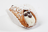 A sweet cannelloni filled with cream, in a paper case