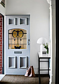 Open front door in the hallway with console table and white table lamp