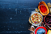 Glass jar of homemade oatmeal granola with fruits and nuts on dark vintage background