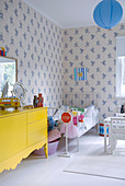 Gelbes Sideboard und Metallbett im Kinderzimmer mit blau-weißer Tapete