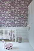 Cot against wall with purple toile de jouy wallpaper