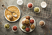 Healthy truffles with dates and nuts covered in sesame seeds, strawberry and matcha powder