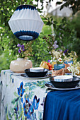 Table set in shades of blue below white and blue lanterns in garden