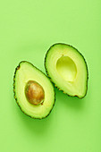 Halbierte Avocado vor grünem Hintergrund (Aufsicht)