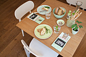 Cutlery pouches with name tags on table set with mint-green crockery