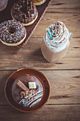 Sweet chocolate donuts and cream coffee on wooden background