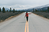 Caucasian woman balancing on stripes in two-lane road