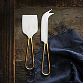 Two different cheese knives on a wooden background (top view)
