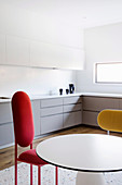 Runder Tisch und Designerstühle in weißer Einbauküche
