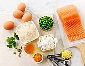 A still life of ingredients for a salmon dish with rice and peas