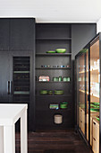 Black fitted kitchen up to the ceiling and showcase with green dishes