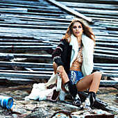 A brunette woman wearing an open gillet, a cardigan and shorts by the sea