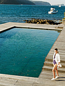 A young woman wearing a bathing suit and a long blouse by a pool