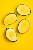 Mango halves against a yellow background (top view)