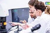 Scientist pointing at computer monitor in lab