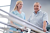 Nurse with senior man using parallel walking bars