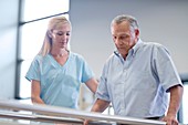 Nurse with senior man using parallel walking bars