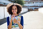 Woman with drink outdoors, smiling