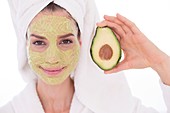 Woman holding avocado with face mask