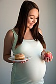 Pregnant teenager with a doughnut and an apple