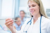 Doctor looking at thermometer and smiling