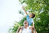 Grandfather carrying grandson on shoulders