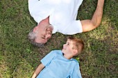 Grandfather and grandson lying on grass