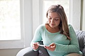 Woman sitting on sofa and looking at pregnancy test