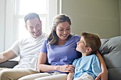 Boy sitting on sofa with his mother and father, portrait