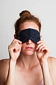 Woman covering her eyes with sleeping mask
