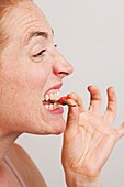Woman biting into red chili